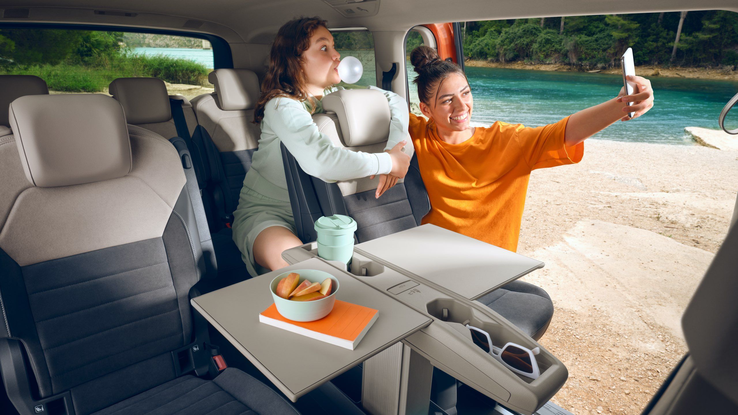 Duas mulheres tiram fotografias no Multivan da Volkswagen com a mesa multifunções dobrada.