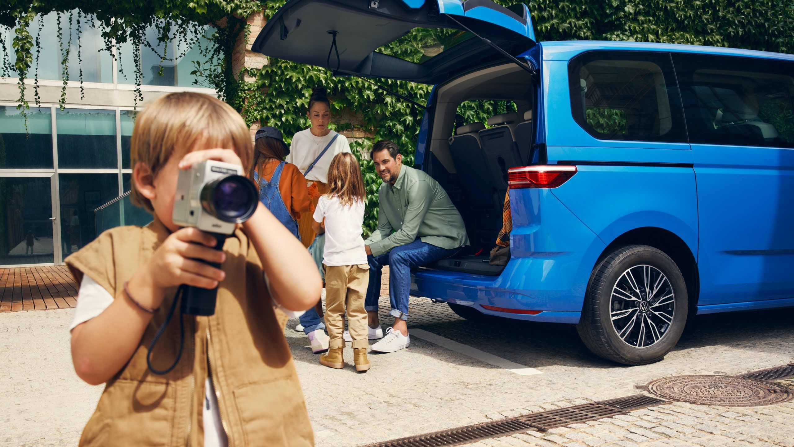 Uma família sentada no porta-bagagens aberto da Multivan da Volkswagen.